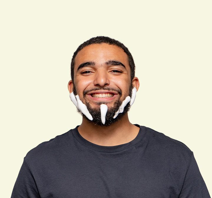 Happy bearded man applying facewash